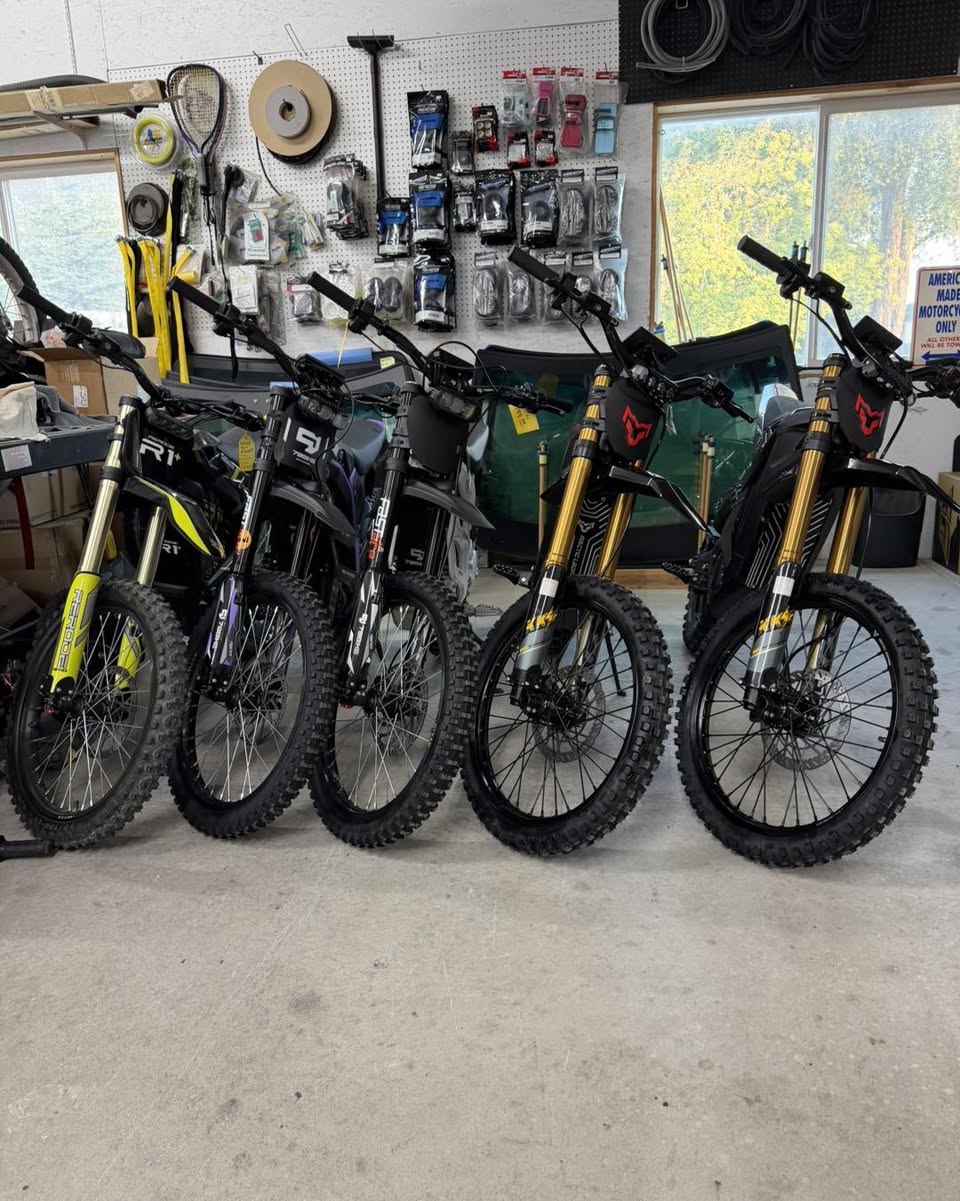 Rerode and 79Bike electric dirt bikes in front of the shop's parts pegboard.