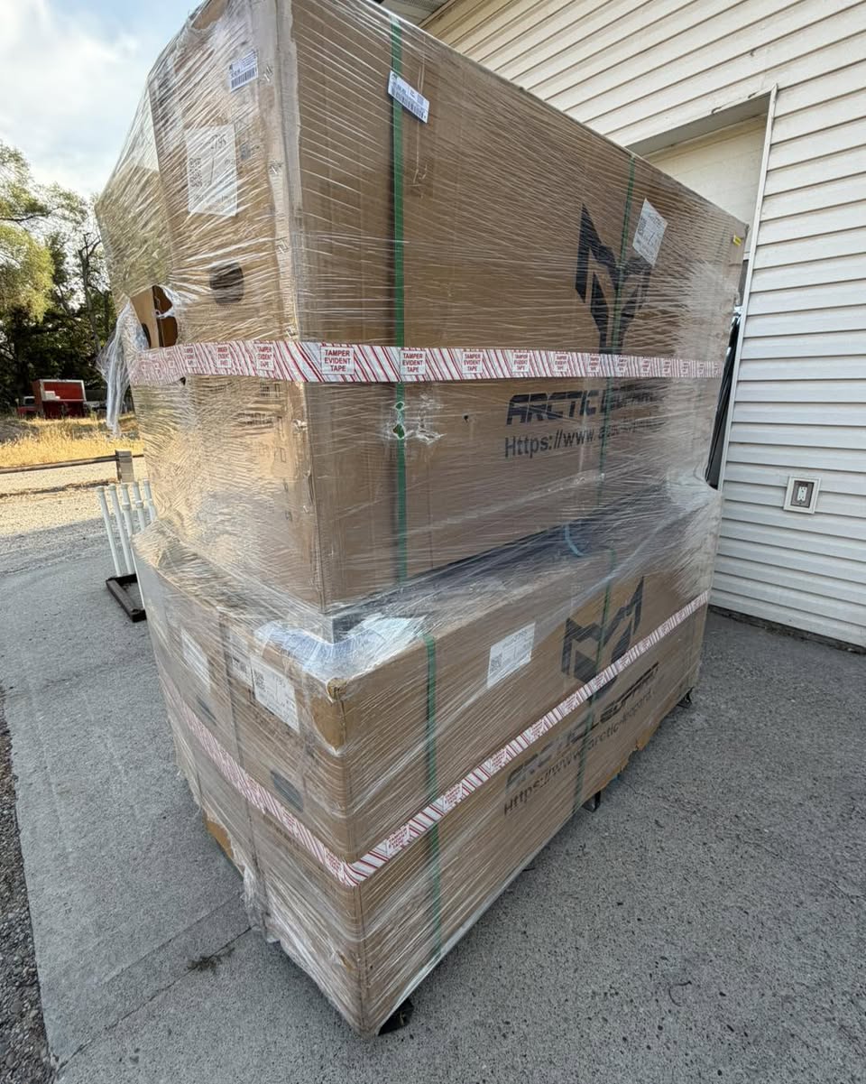 A shrink-wrapped pallet of crated Arctic Leopard electric dirt bikes delivered behind the shop.